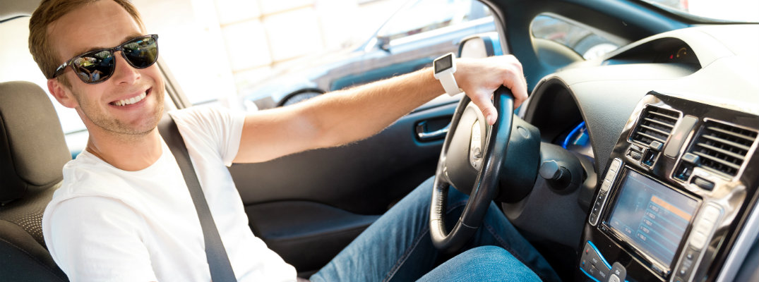 Young driver wearing a pair of sunglasses while driving