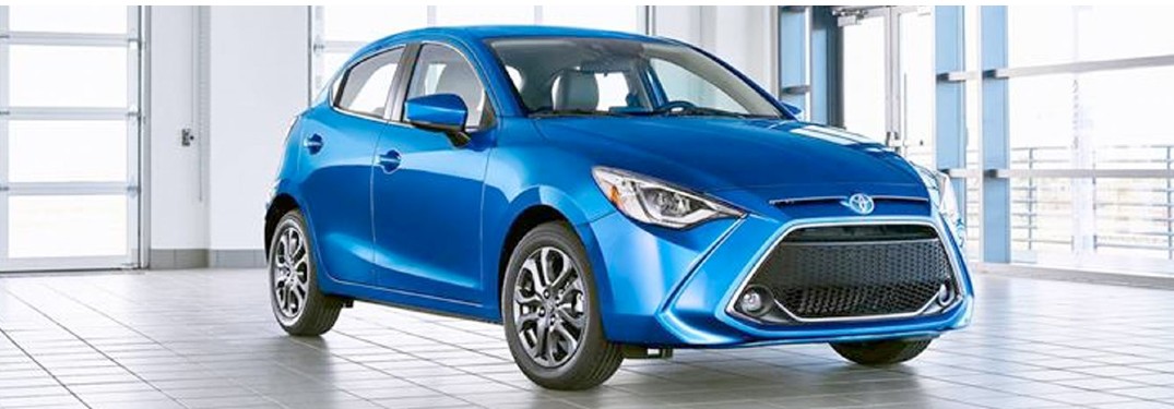 A blue-colored 2020 Toyota Yaris parked in an enclosed building with many windows in the background