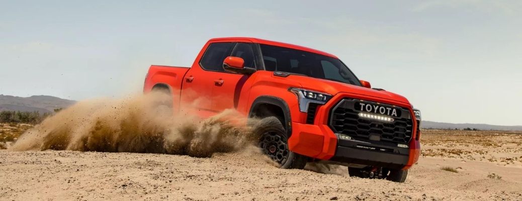 A red 2022 Toyota Tundra driving in the sand.