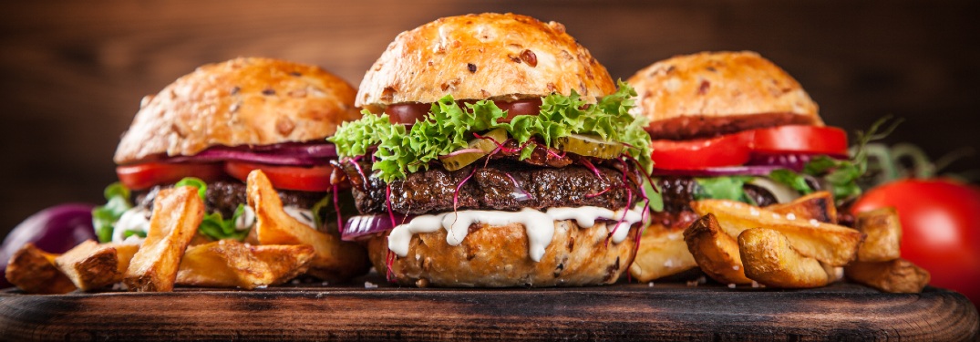 Three delectable burgers spread out on a table looking artisanal.