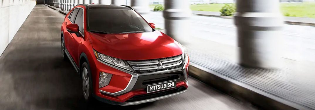 Red 2020 Mitsubishi Eclipse Cross driving through an ancient building.