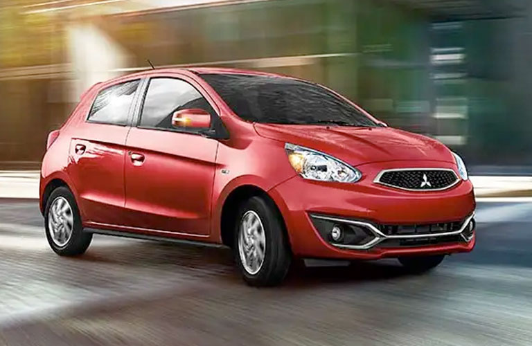 Red 2020 Mitsubishi Mirage zips along a city street. 