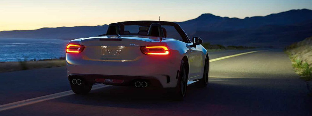 Rear view of 2018 Fiat 124 Spider driving at dusk