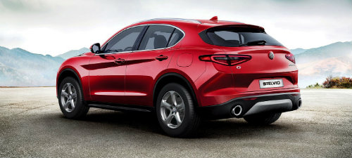 Rear profile shot of red Alfa Romeo Stelvio parked against mountainous backdrop
