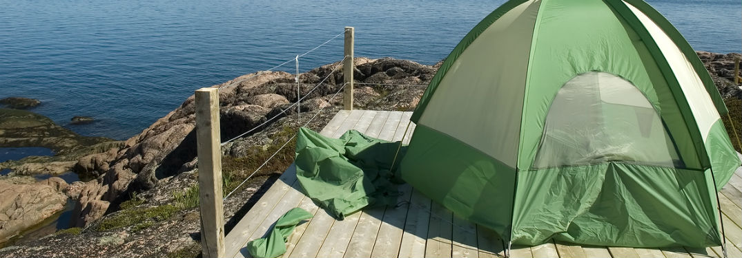 backpacking tent on wooden platform on hill overlooking water