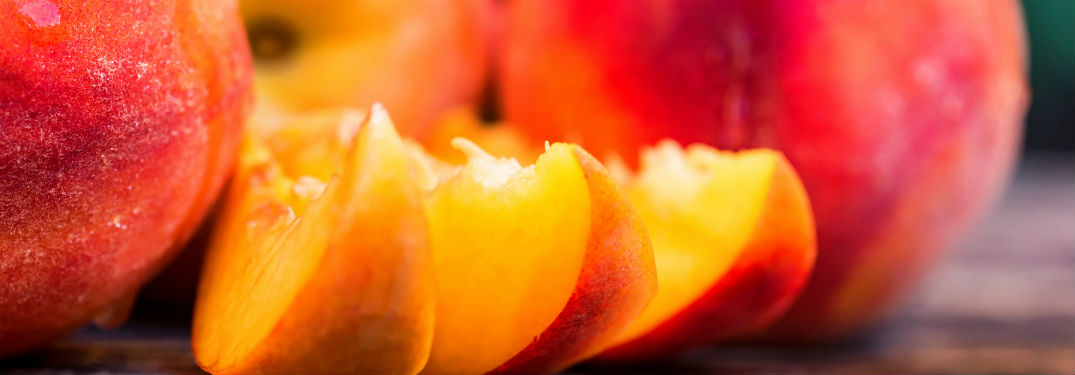 close up of three slices of peaches with whole peaches in background