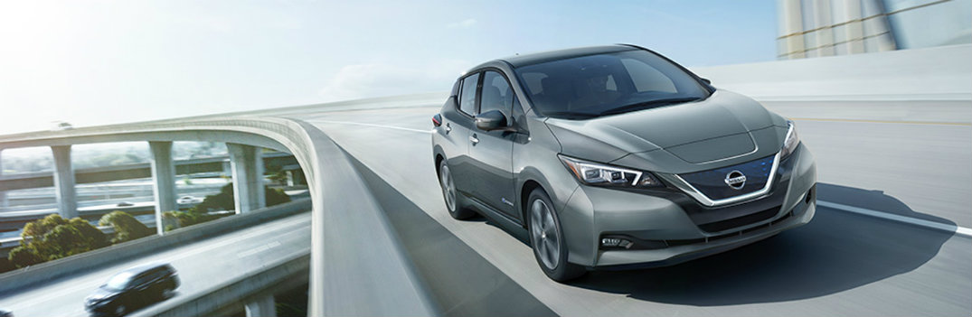 2018 Nissan LEAF driving on a connected highway bridge under a bright sun in the city