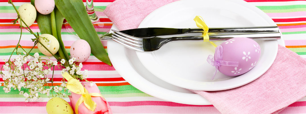 Easter dinner table setting with bright colors, fork and knife, and eggs