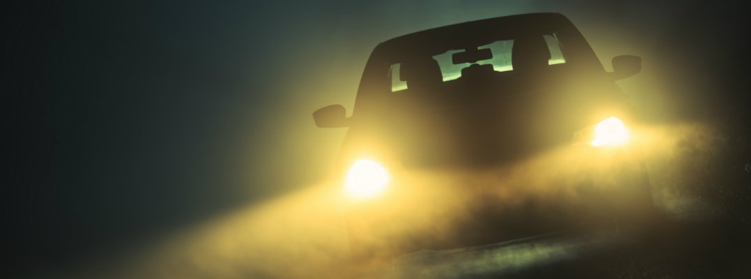 car driving at night in the dark with headlights on
