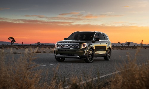 2020 Kia Telluride exterior shot with dark green paint color parked on a country highway as the sun sets