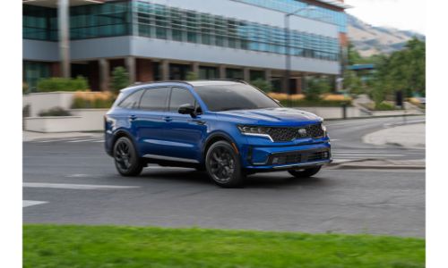 2021 Kia Sorento exterior shot with blue paint color driving past a building near a grass field
