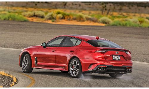 2021 Kia Stinger GT2 RWD exterior rear shot with red paint color driving on a country highway