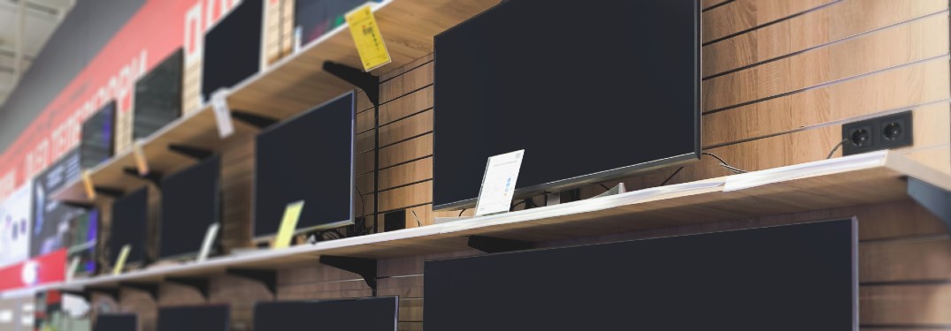 shelves of flatscreen TV models on a wall of an electronics store