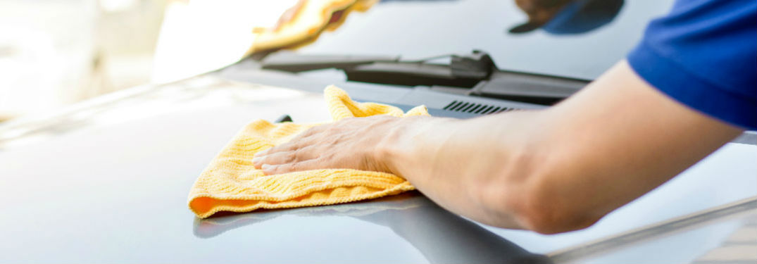 person wiping car with cloth