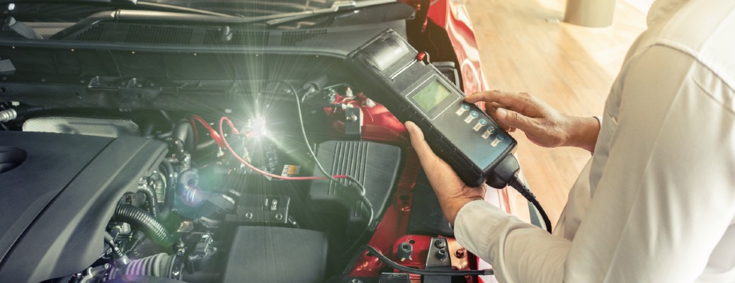 two hands holding a tool over a vehicle engine