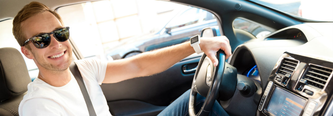 man smiling holding steering wheel