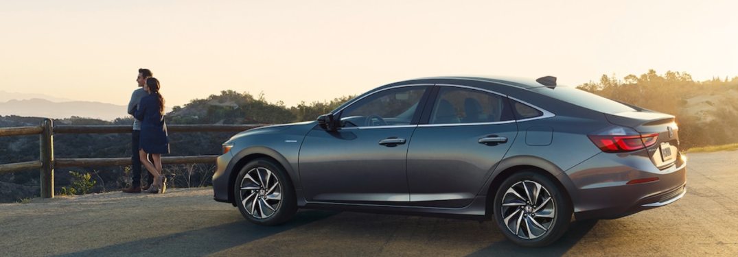A woman standing next to a 2021 Honda Insight parked in a lot