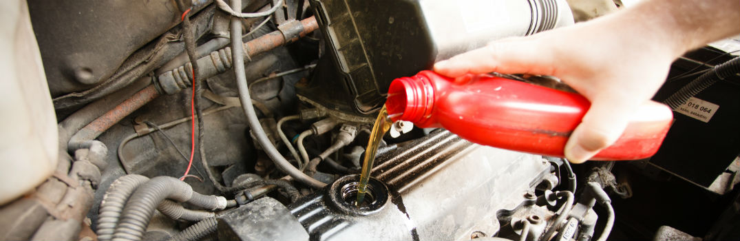 person pouring oil in a vehicle engine