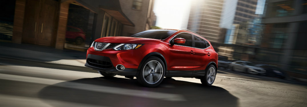 left side view of red nissan rogue sport on city street