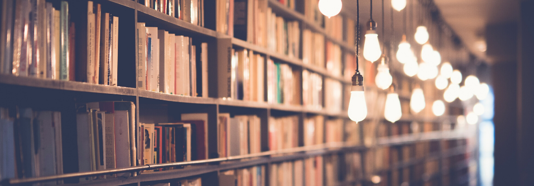 A crowded bookshelf in a dimly lit library