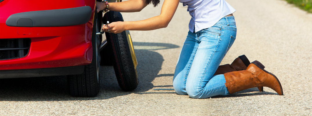 Young Woman Changing a flat tire on the highway