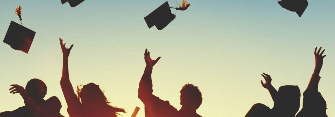 College grad silhouettes throwing caps into air