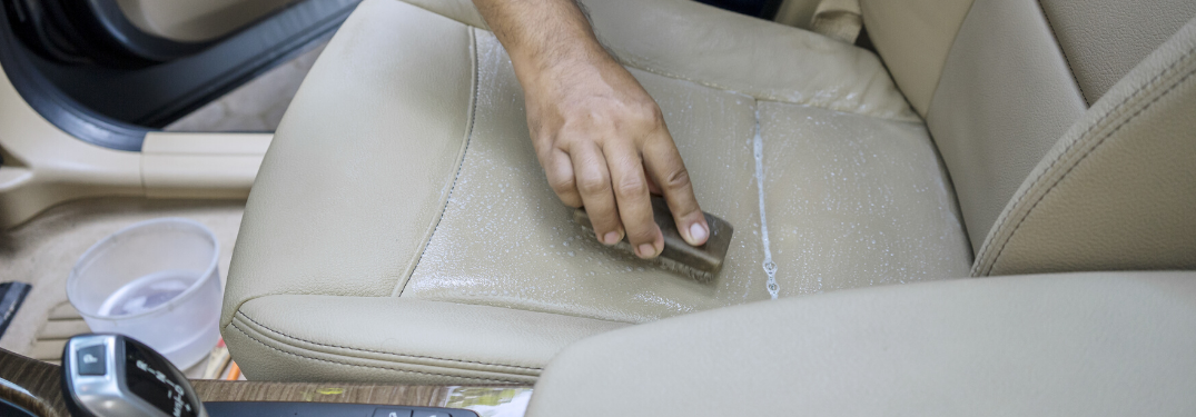 A hand cleaning up a car seat