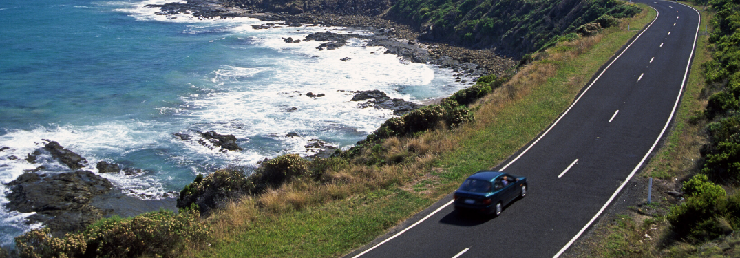 A vehicle driving down a beachside road