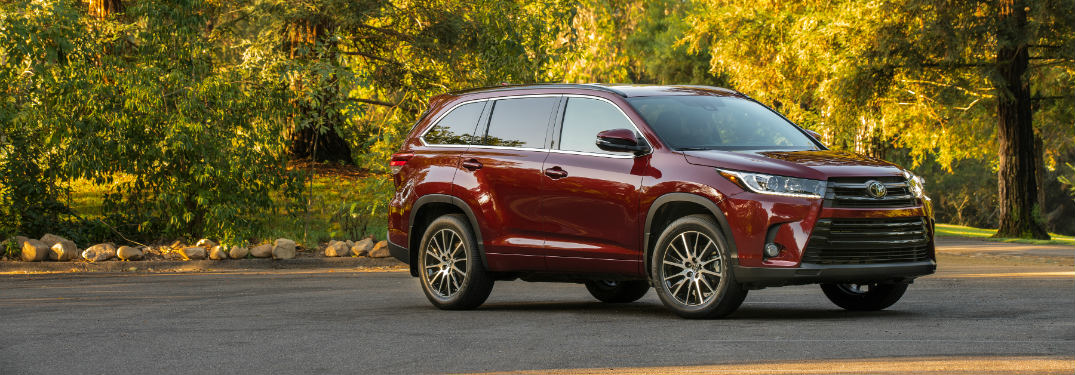 red 2018 toyota highlander in front of green and yellow trees