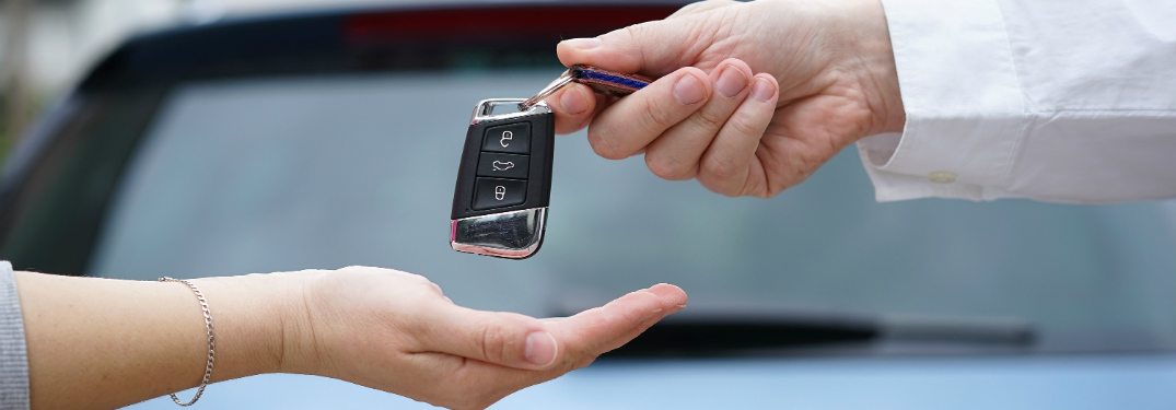 man handing over car keys to woman