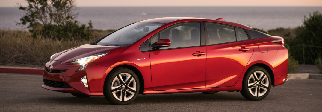 red 2018 toyota prius with ocean behind it