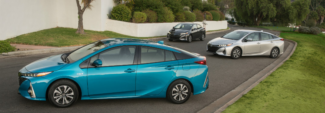 turquoise, white and silver 2018 toyota prius prime parked together in driveway of large hosue
