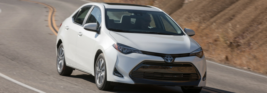 white 2018 toyota corolla driving down hill road