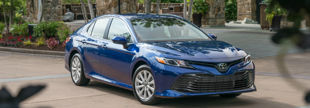 blue 2018 toyota camry parked in stone driveway surrounded by plants and trees