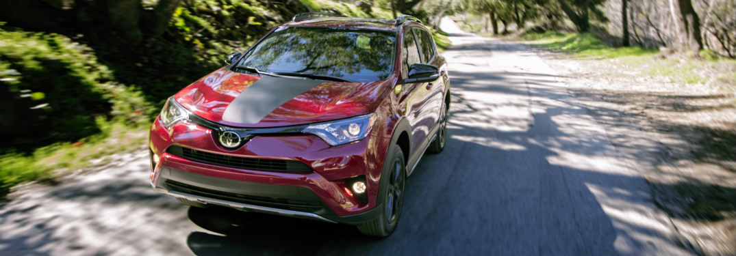 front view of red and black 2018 toyota rav4 driving on forest road