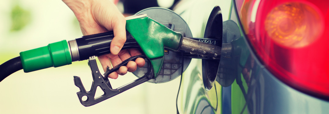 person filling up gas tank in car with green gas station nozzle