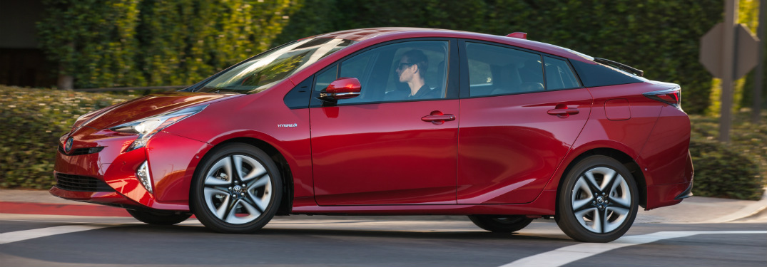 side view of red 2018 toyota prius in front of bushes