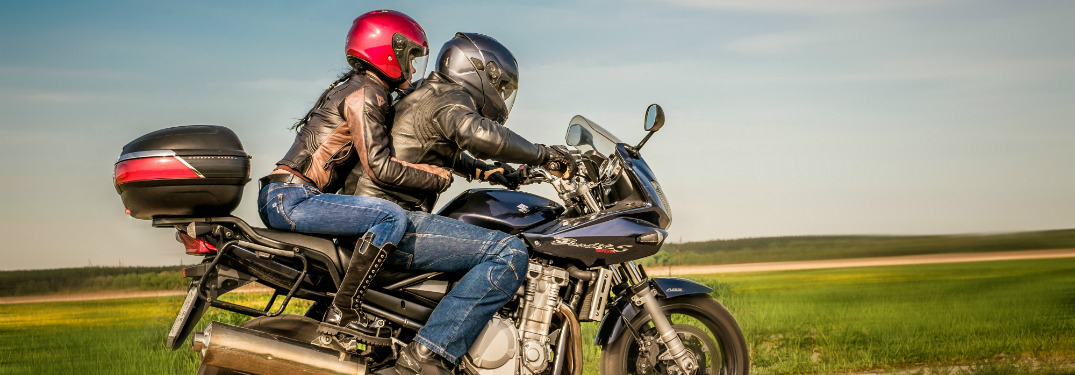 man and woman riding on motorcycle in open country road