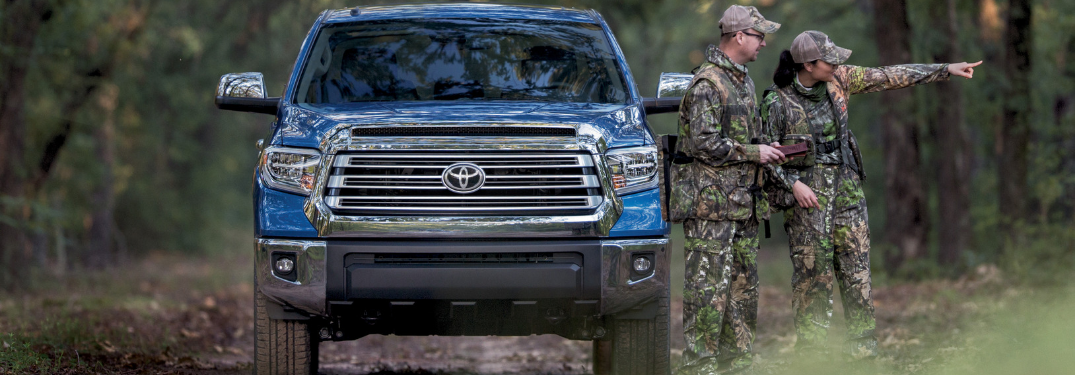 front view of blue 2019 toyota tundra with man and woman in camo gear next to it
