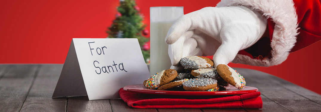 "For Santa" sign with Santa grabbing cookies off of a plate