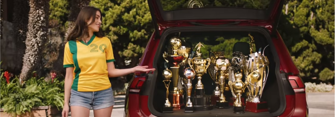 woman in jersey with trophies in the back of vehicle