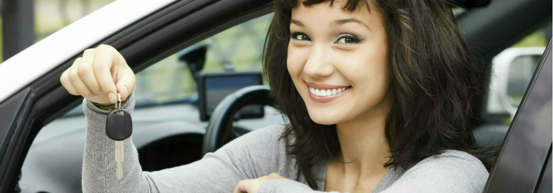 A woman sitting in a car holding a key