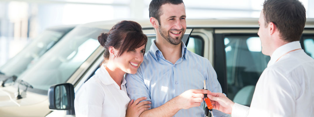 A stock photo of people getting the keys for their new car.
