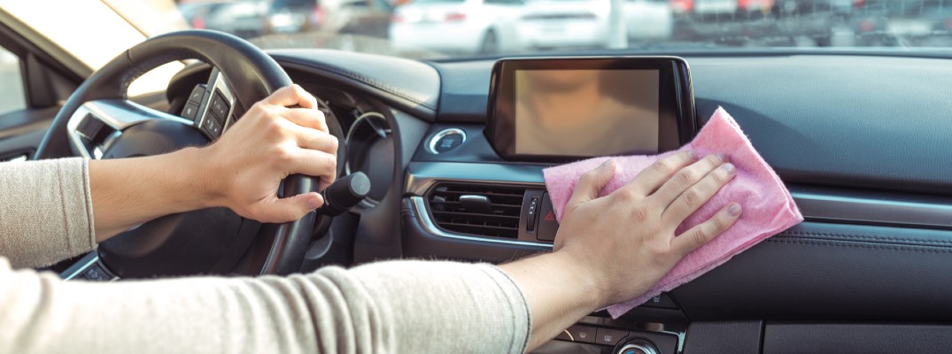 A photo of a person wiping down the inside of a car before or after a test drive.