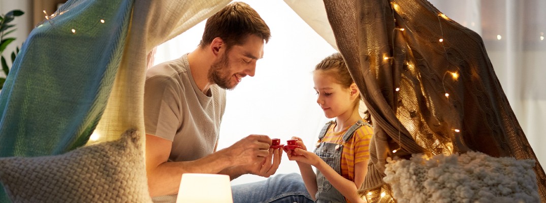 A stock photo of a dad spending time in a blanket fort.