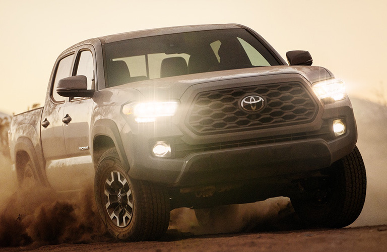 A head-on photo of the 2020 Toyota Tacoma driving through sand.