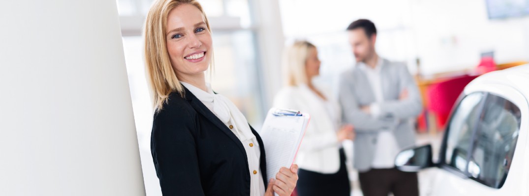 A stock photo of a person helping people at the dealership.