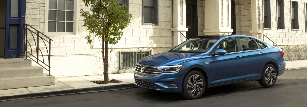 blue jetta parked by tree and building