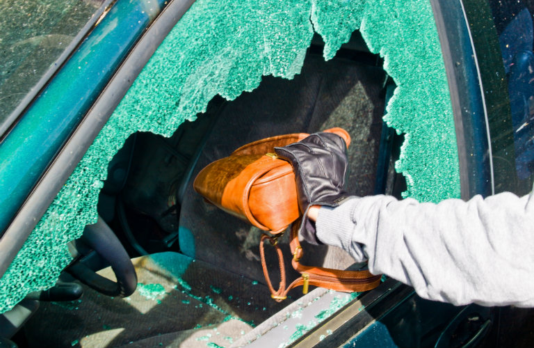 person taking purse through broken car window