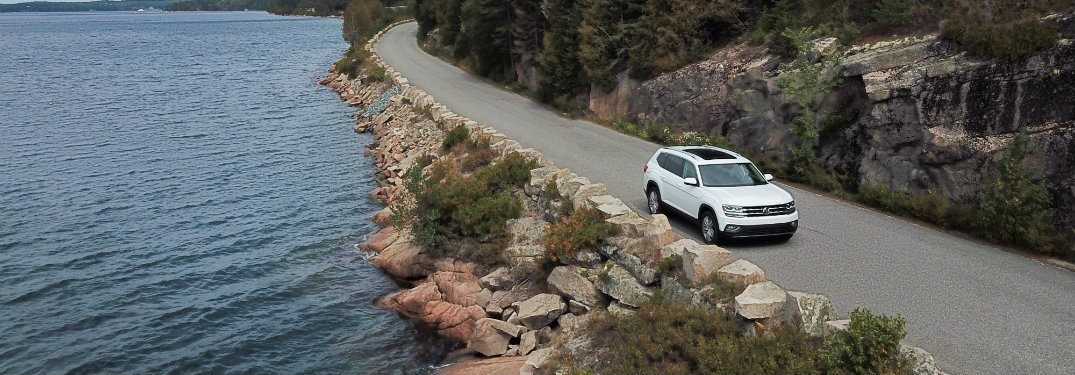 white volkswagen atlas on road by water